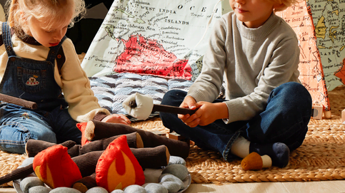 A boy and girl playing with a pretend campfire toy.