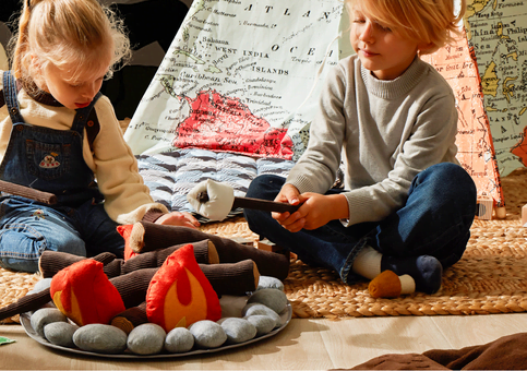 A boy and girl playing with a pretend campfire toy.