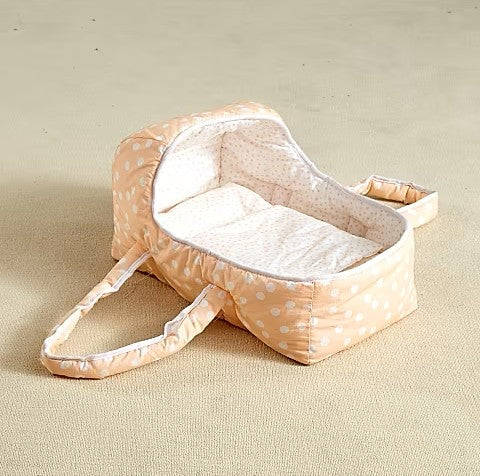 Baby doll carrier with peach polka dot pattern and white bedding interior