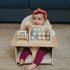 Child playing with a wooden abacus toy sitting in the supportive baby activity chair designed for sitting, playing, and snack time.