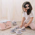 Young girl playing with plush tea set for toddlers in pink and floral pattern on floor