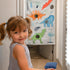 Young girl playing doorway bean bag toss with colorful dinosaur design on door frame