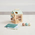 Wooden activity cube for toddlers with balls, fabric squares, and colorful side wheels