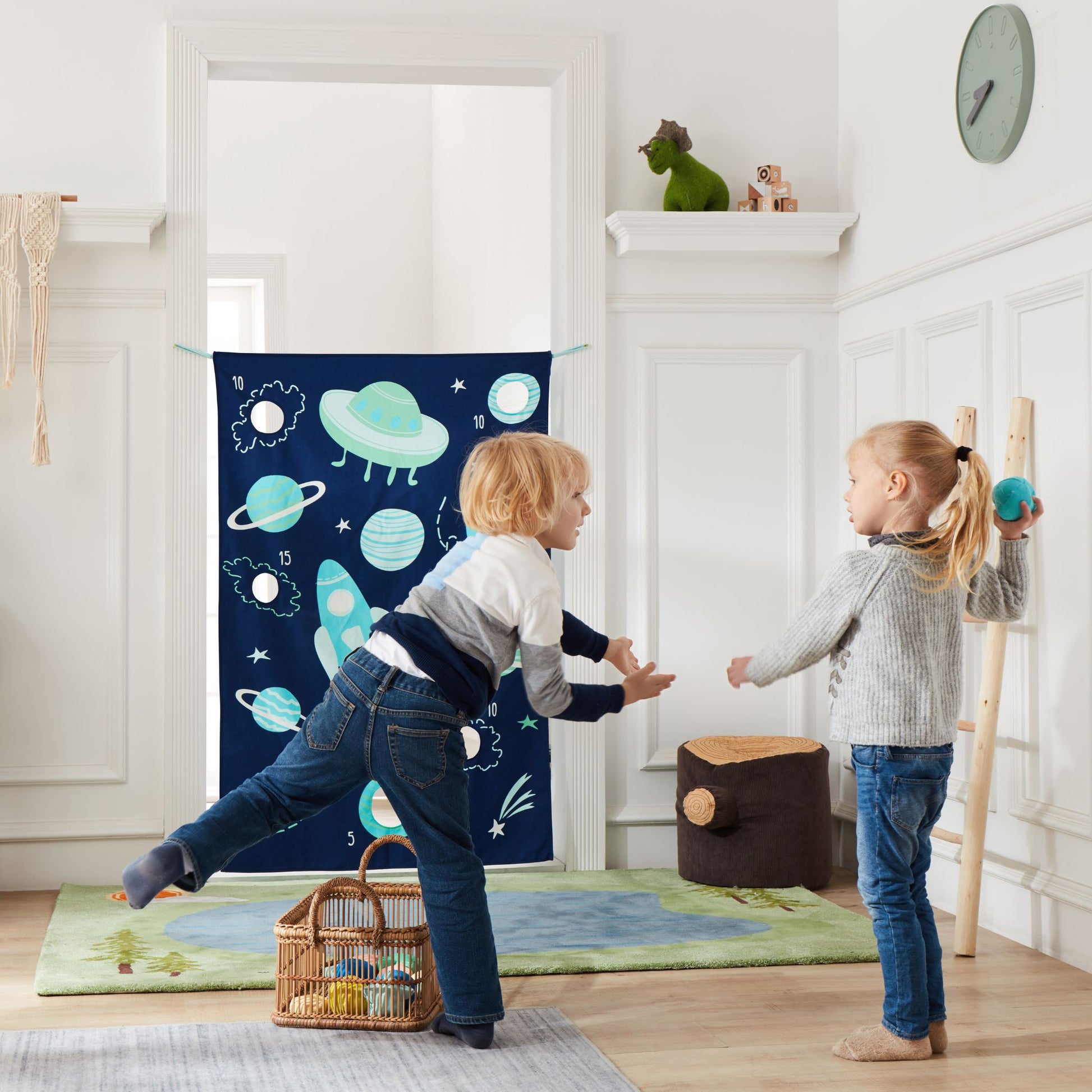 Children playing with space-themed doorway bean bag toss game on door frame