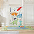 Dino Doorway Bean Bag Toss game hung between white doors with colorful dinosaur and plant designs, balls scattered on green play mat