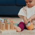 Baby playing with wooden block toy set in cream and colorful blocks on beige rug