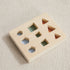 Wooden shape sorting toy with hexagon, square, and triangle cutouts in natural and pastel colors