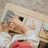 Child playing with wooden educational toys including a peek-a-boo mirror on the table of the little wood chair.