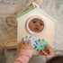 Toddler playing with wooden activity cube featuring mirror and gear toys in pastel colors