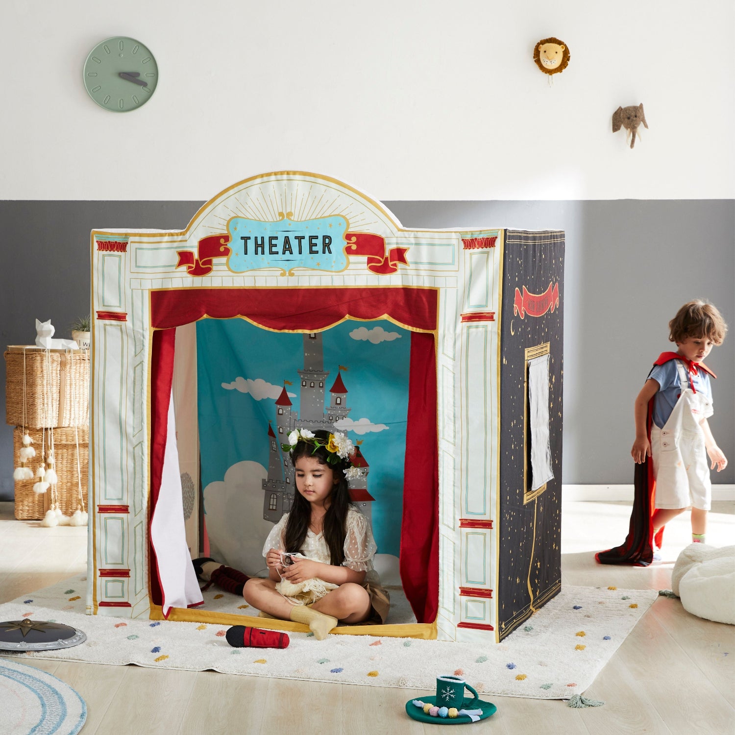 Children's playhouse with a theater sign and curtains, with two children playing inside.
