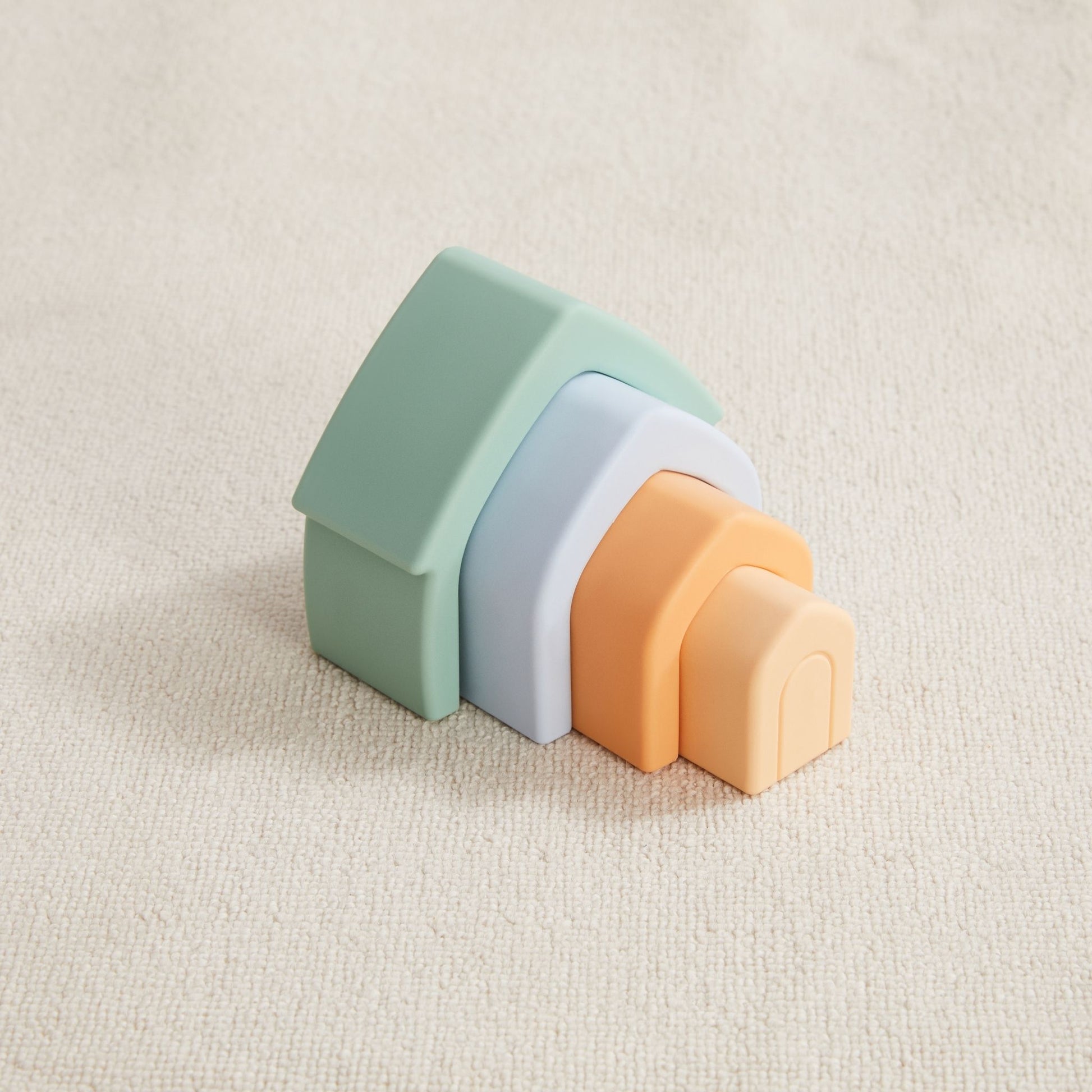 Colorful nesting houses in green, white, orange and cream displayed together on textured background