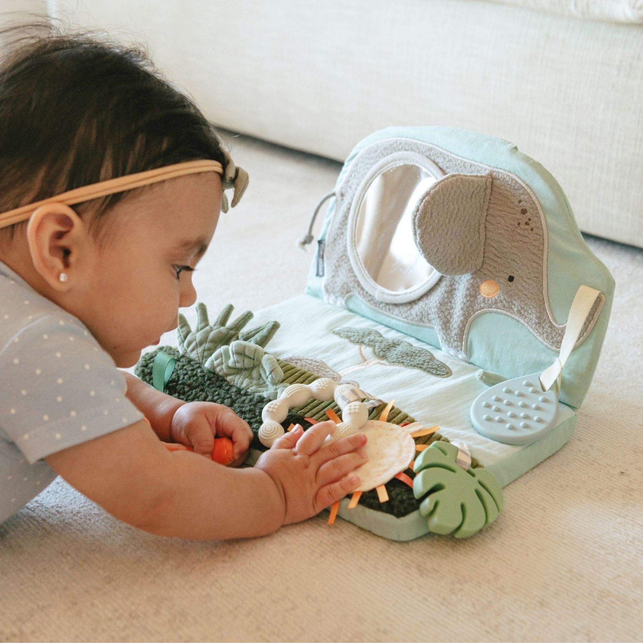 Baby playing with elephant-shaped tummy time sensory toy in soft pastels