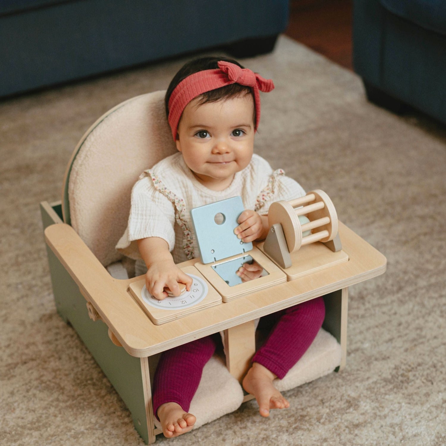 Baby sitting in a high chair with educational toys.