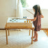 Child playing with Cool Pool game set on top of the wooden Land, Sand and Water Table in a bright room