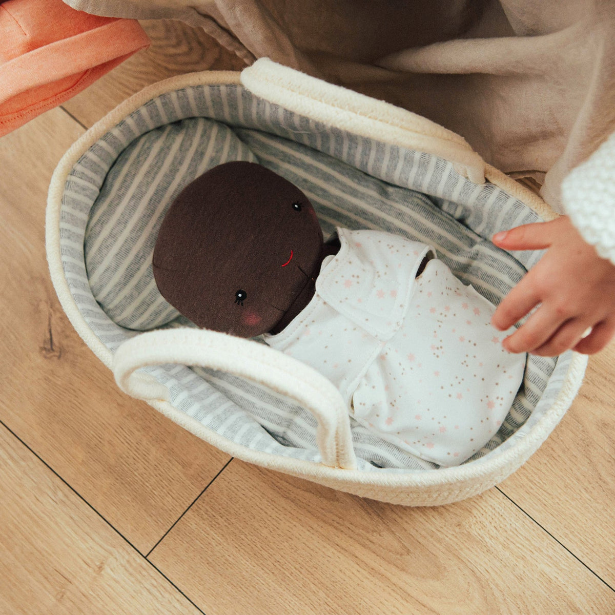 Overhead view of the Sweet Pea doll lying in the Doll Carrier and Bundle Baby Sweet Pea carrier as a child reaches in