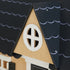 Close-up of the Dollhouse dormer with a round white window set into the black scalloped roof