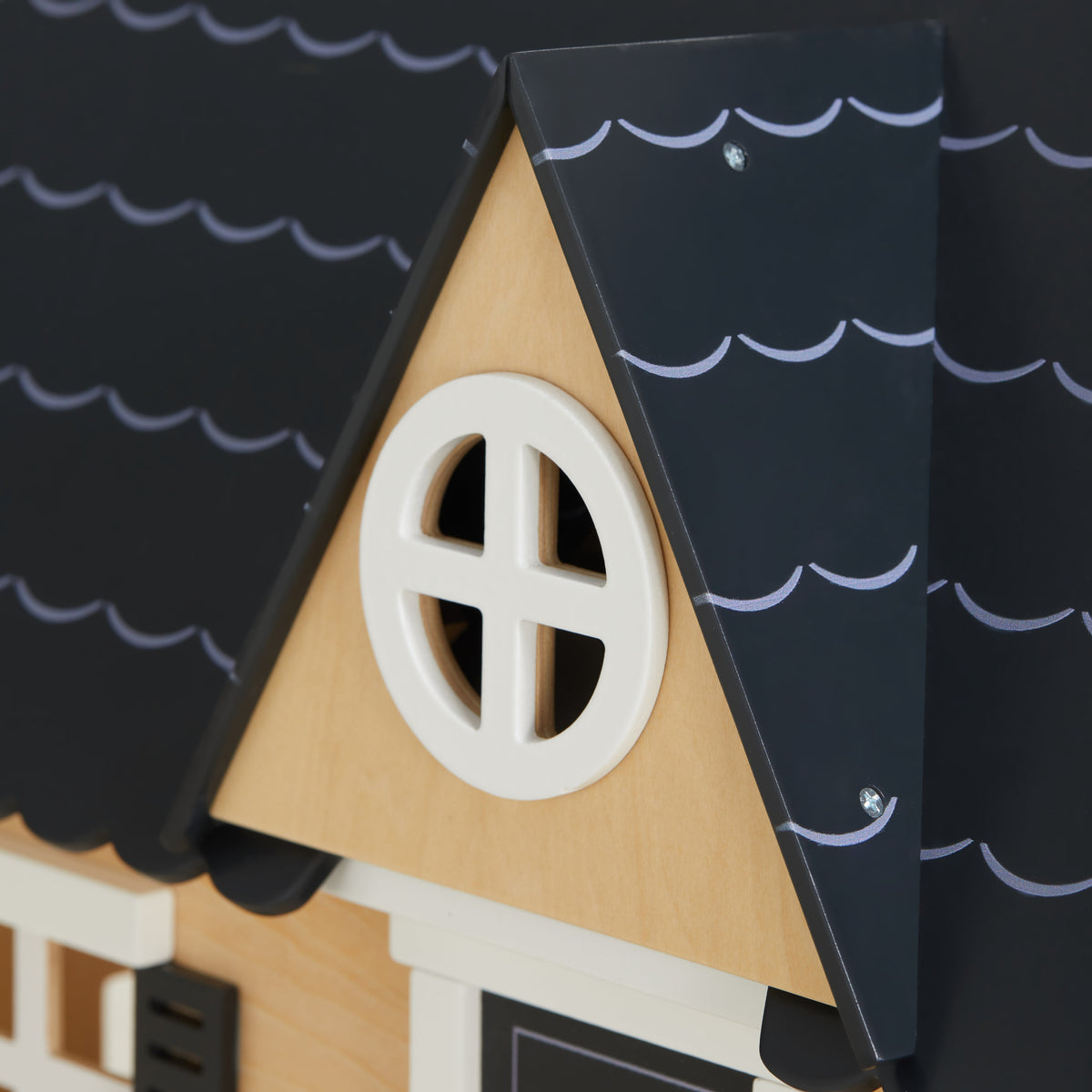 Close-up of the Dollhouse dormer with a round white window set into the black scalloped roof