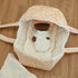 Sweet Pea doll tucked inside the peach Dots and Rainbows Doll Carrier with its blanket on a wood floor