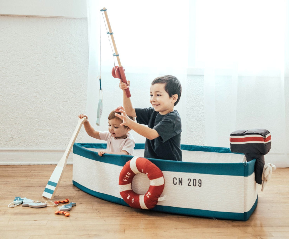 Two children fishing from the Gone Fishing Boat on a wood floor by a bright window