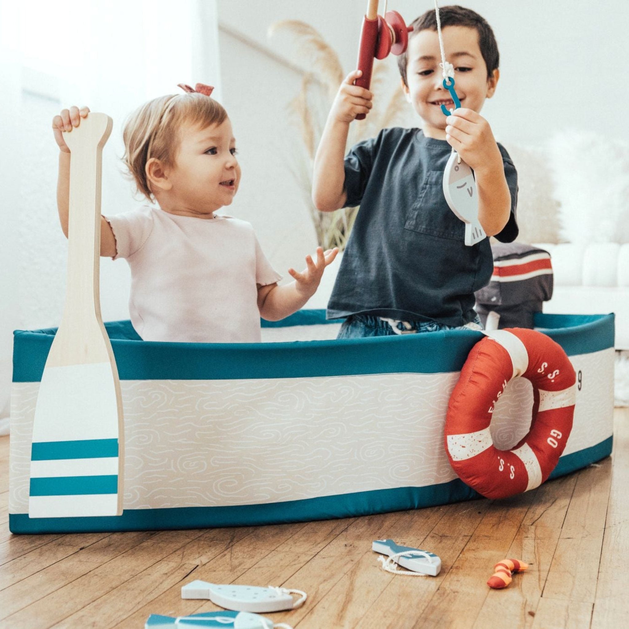 Two children in the Gone Fishing Boat, one holding the wooden oar and one casting a fishing rod
