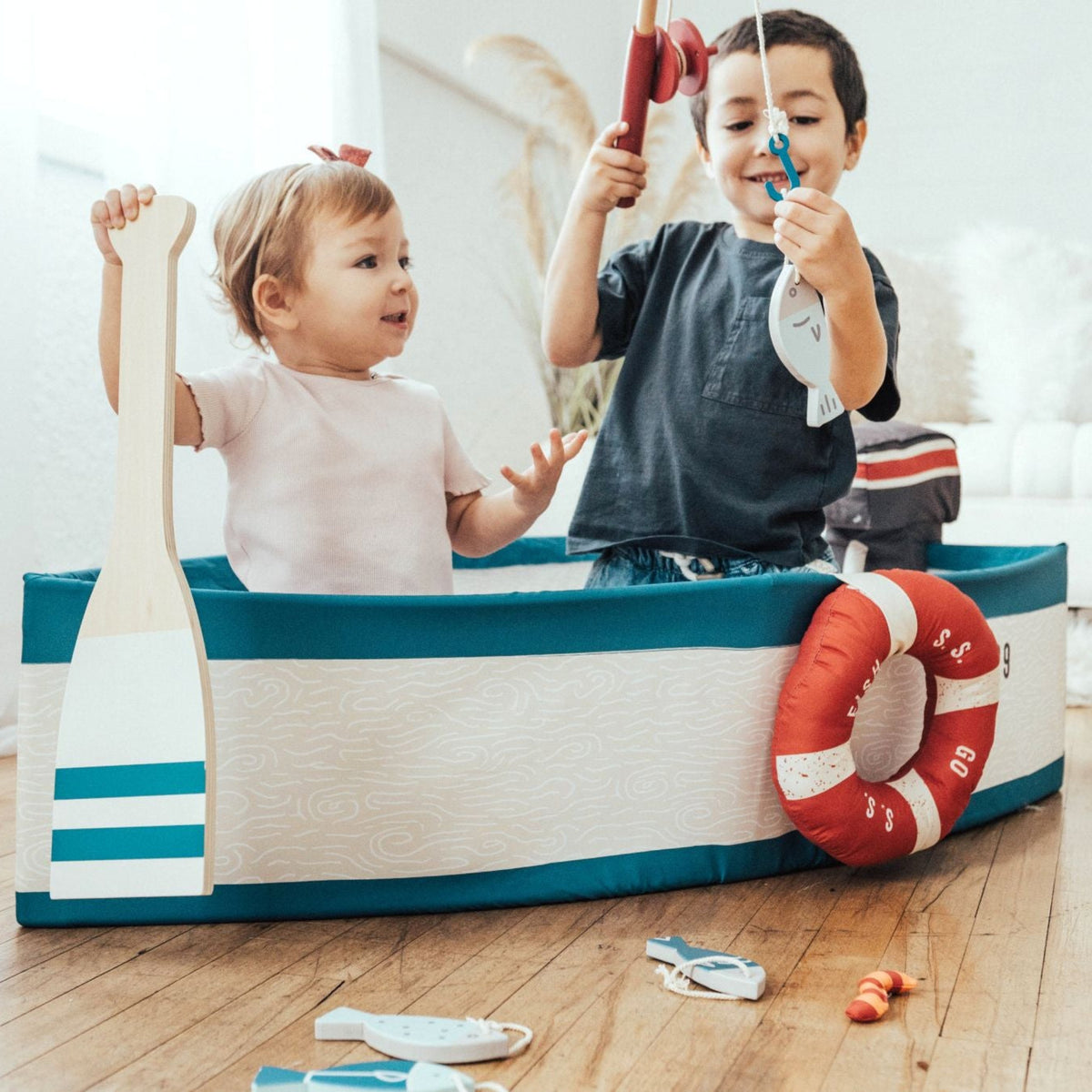 Two children in the Gone Fishing Boat, one holding the wooden oar and one casting a fishing rod
