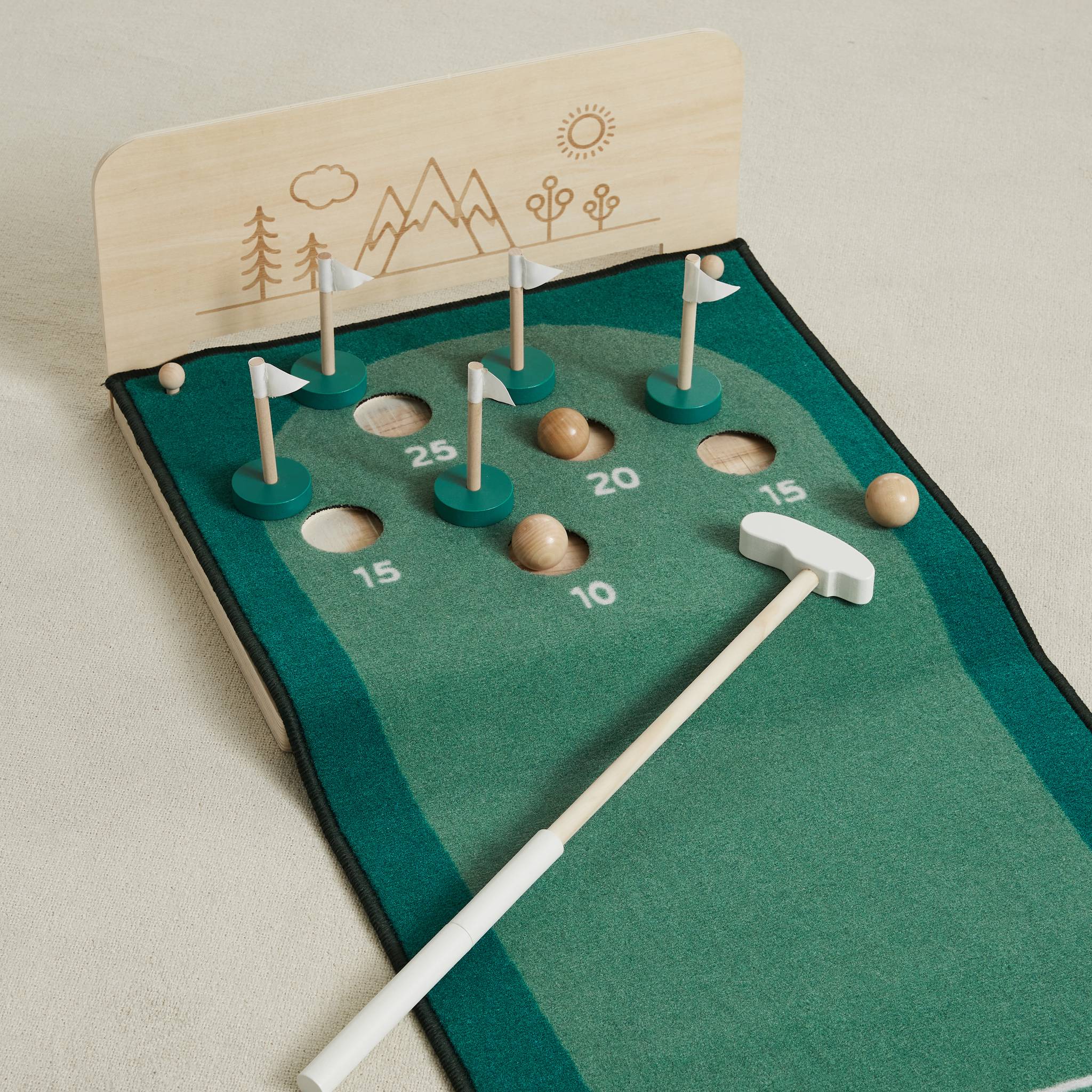 Close-up of the Keen Putting Green's numbered holes, white flags and a wooden ball beside the putter head
