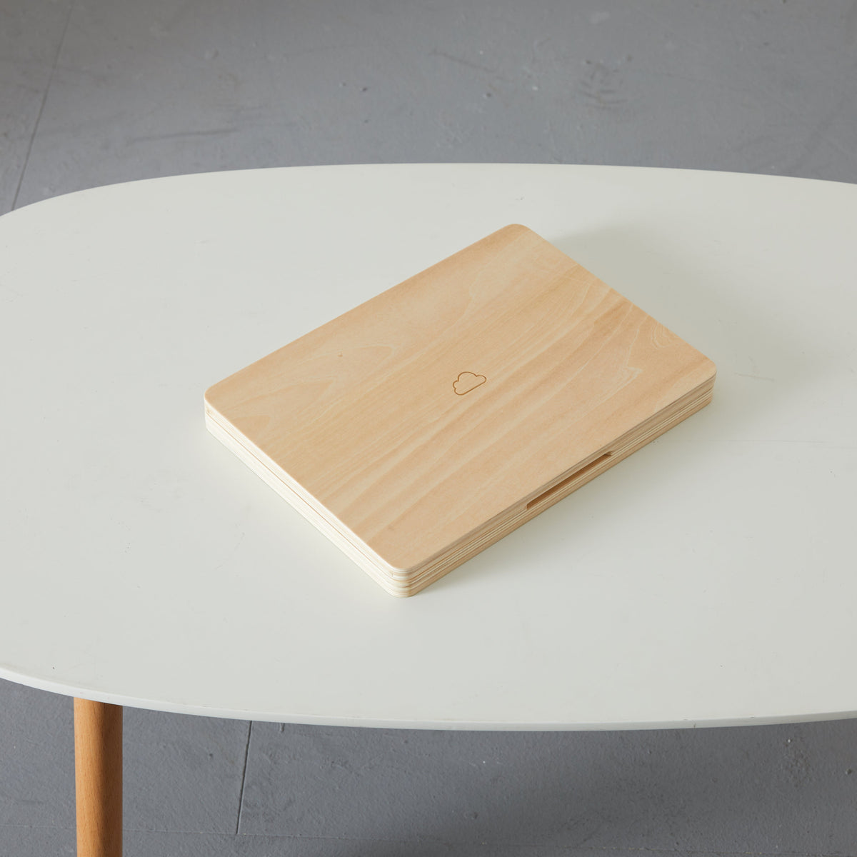 Nonstop Laptop closed on a white table, showing the plain wood lid with a small cloud mark