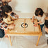 Two children playing Sling-a-Ling Hockey with adults at the Land, Sand and Water Table
