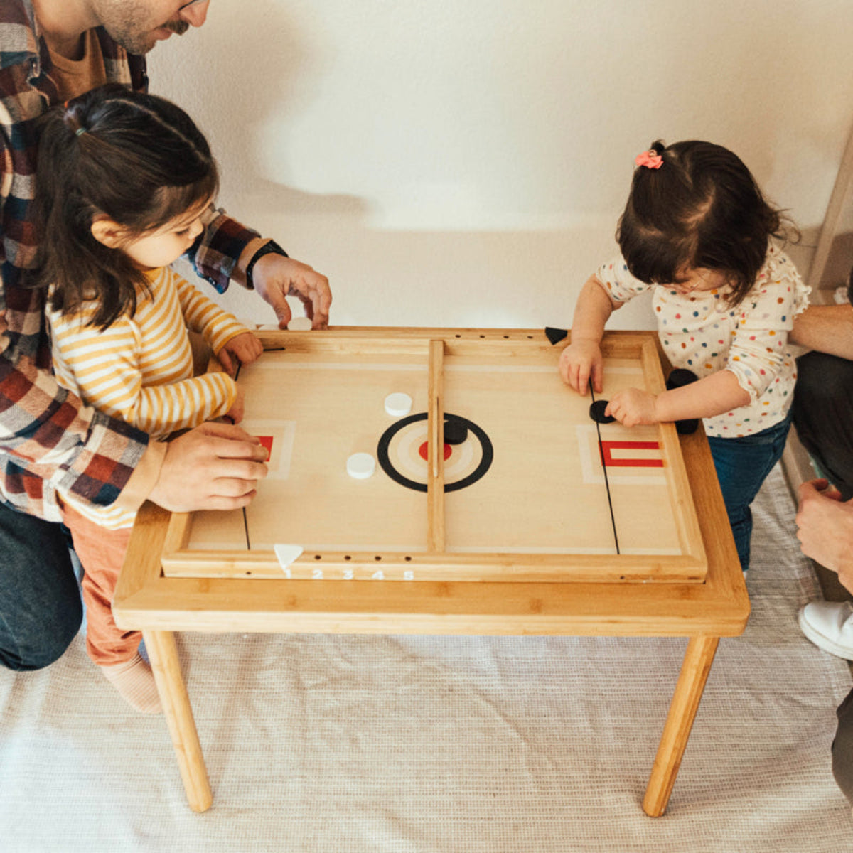 Two children playing Sling-a-Ling Hockey with adults at the Land, Sand and Water Table
