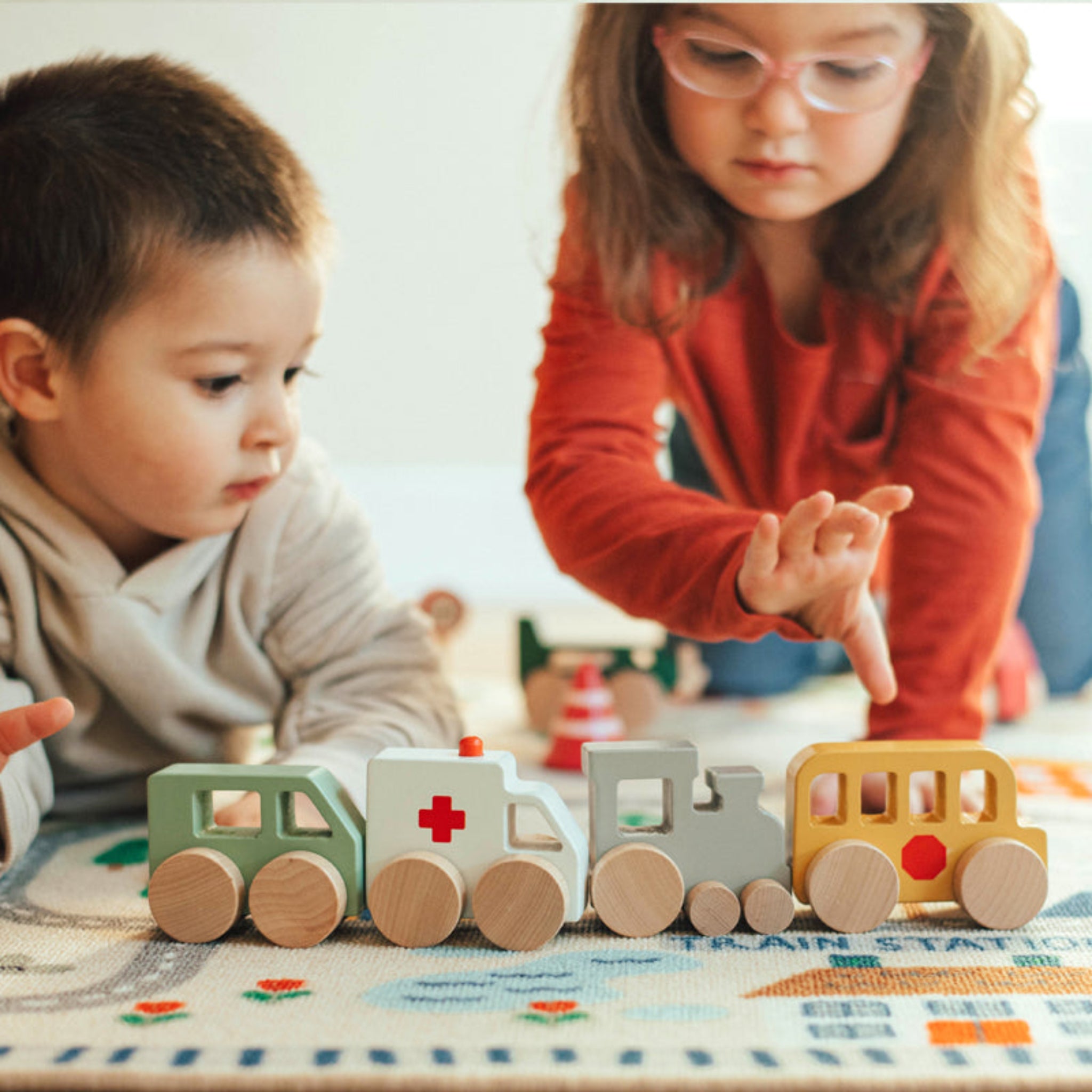 Kids playing with wooden toy vehicles on a town play mat