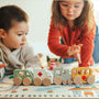 Kids playing with wooden toy vehicles on a town play mat