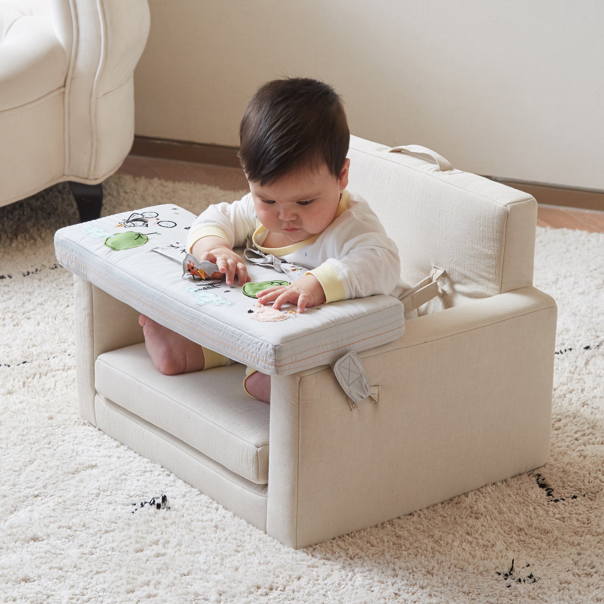 Baby seated in the Rolling Along Square Chair playing with the activity tray on a shag rug