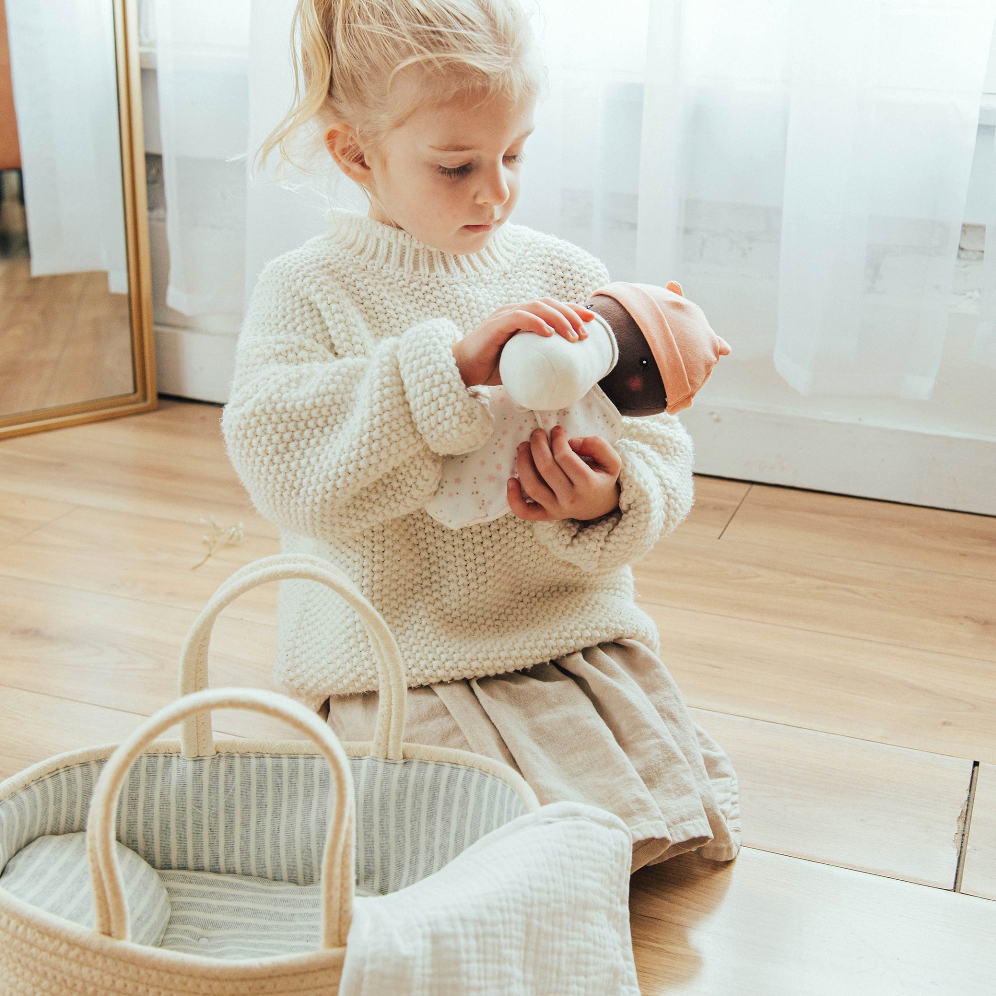 Blonde girl feeding sweet pea doll with bottle in nursery scene