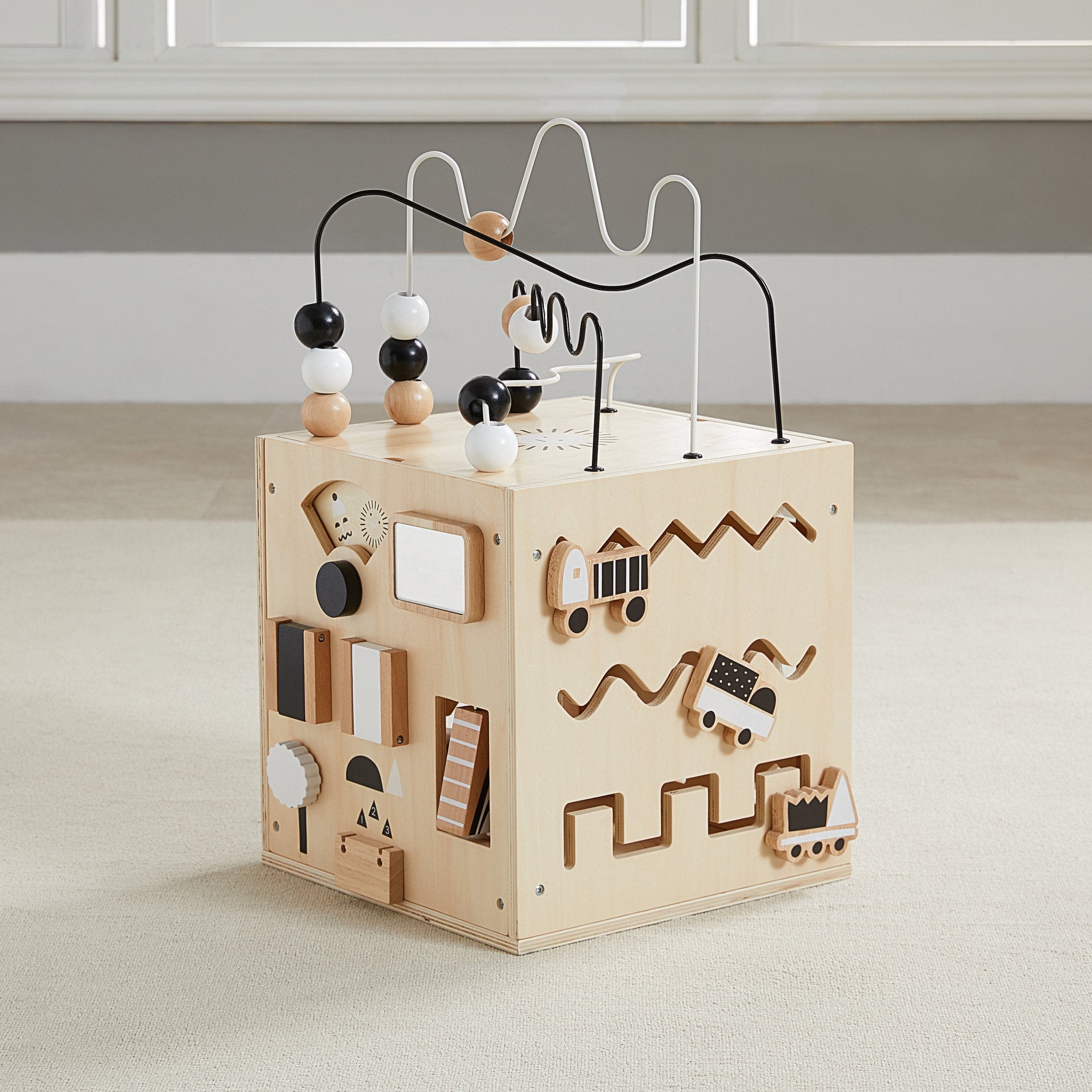 Busy Box activity cube showing the vehicle track panel and the flip-block panel, on a beige floor