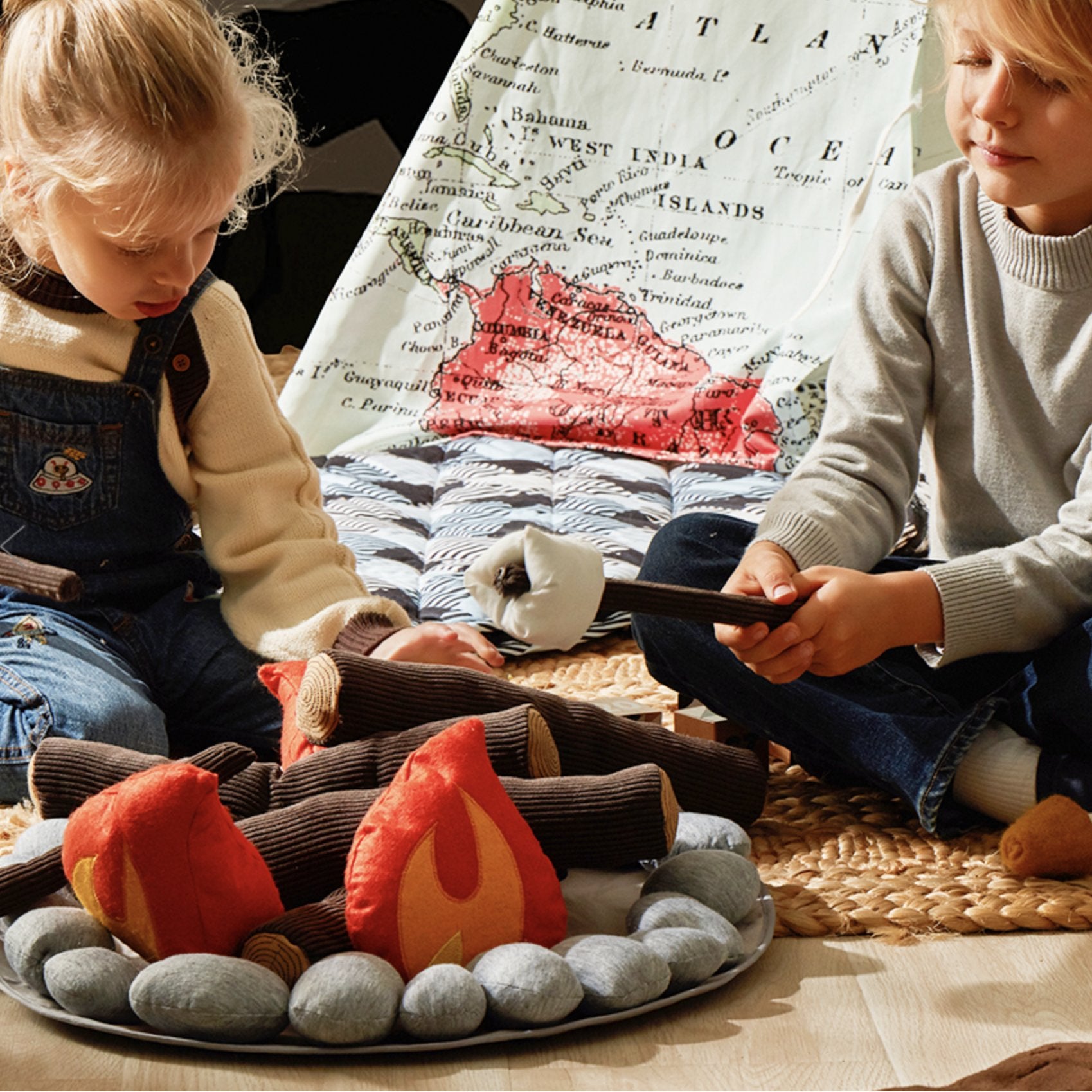 Two children roast plush marshmallows over the Campout Campfire and S'mores set beside a map-print play tent