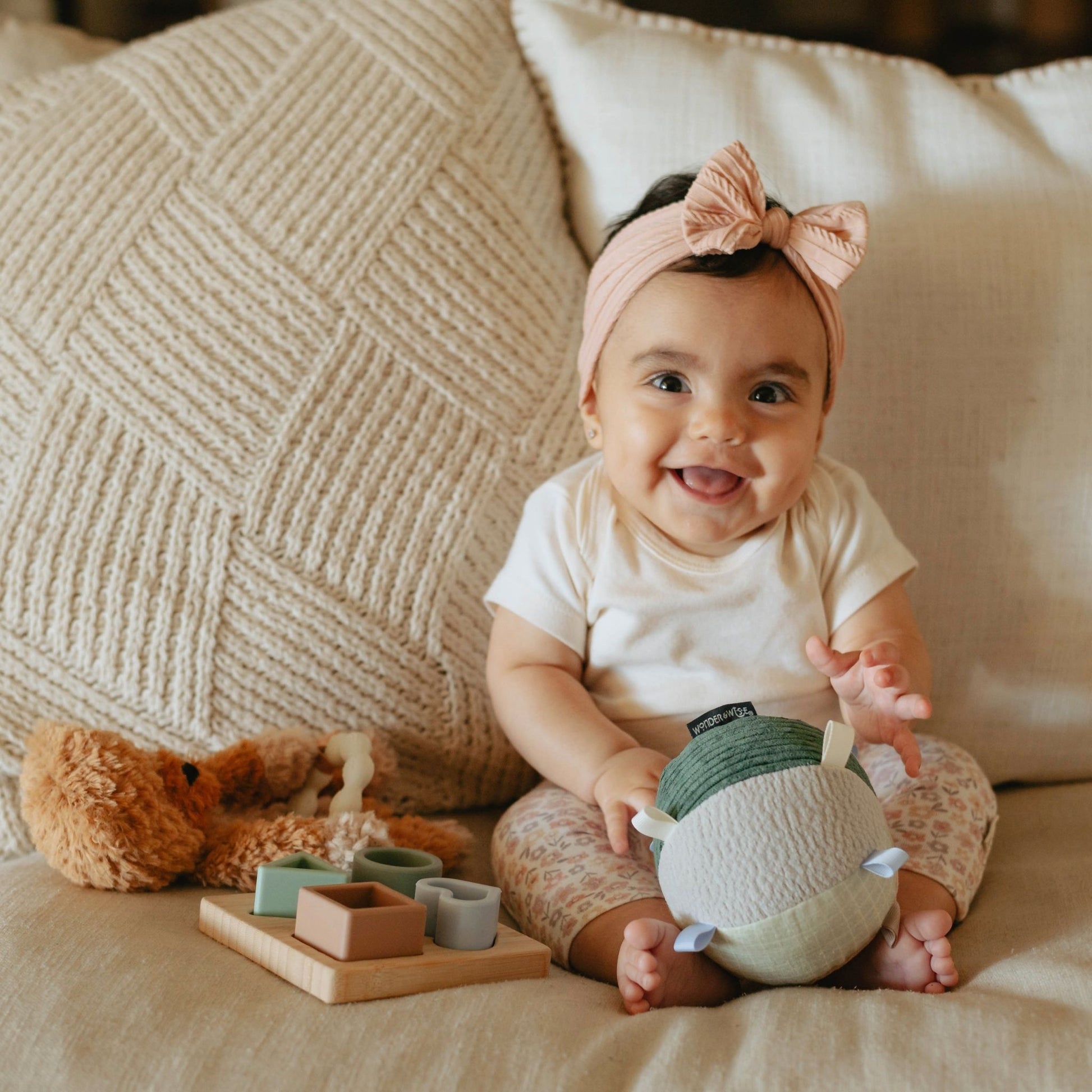 Happy baby playing with soft toys and wooden blocks from Hello Baby gift set for 6-9 months