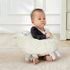 Baby sitting on white llama stuffed animal plush toy in nursery