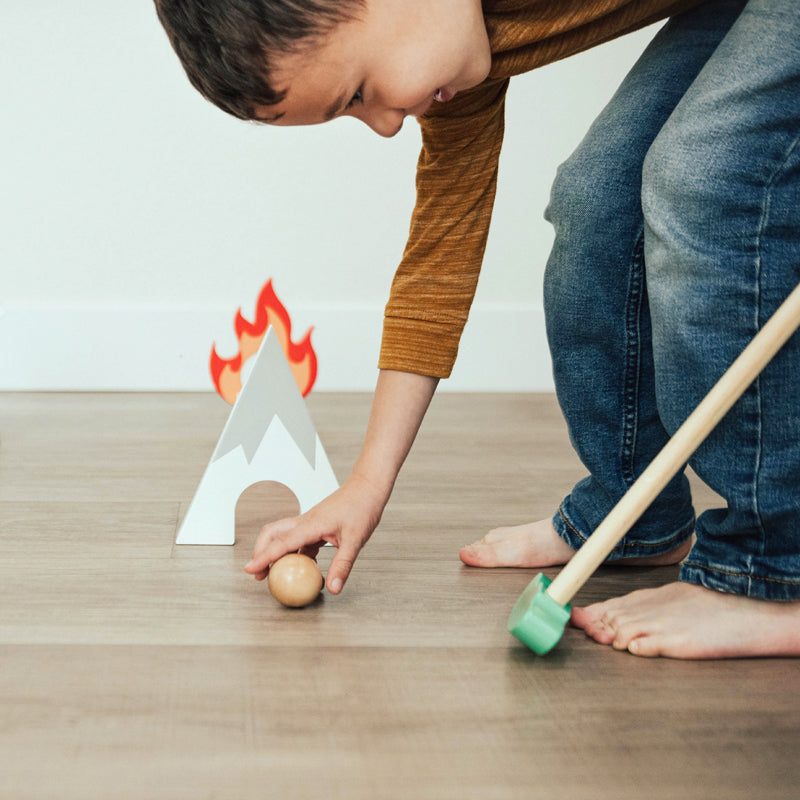 Child playing putt putt golf on a kids putting green with wooden toys