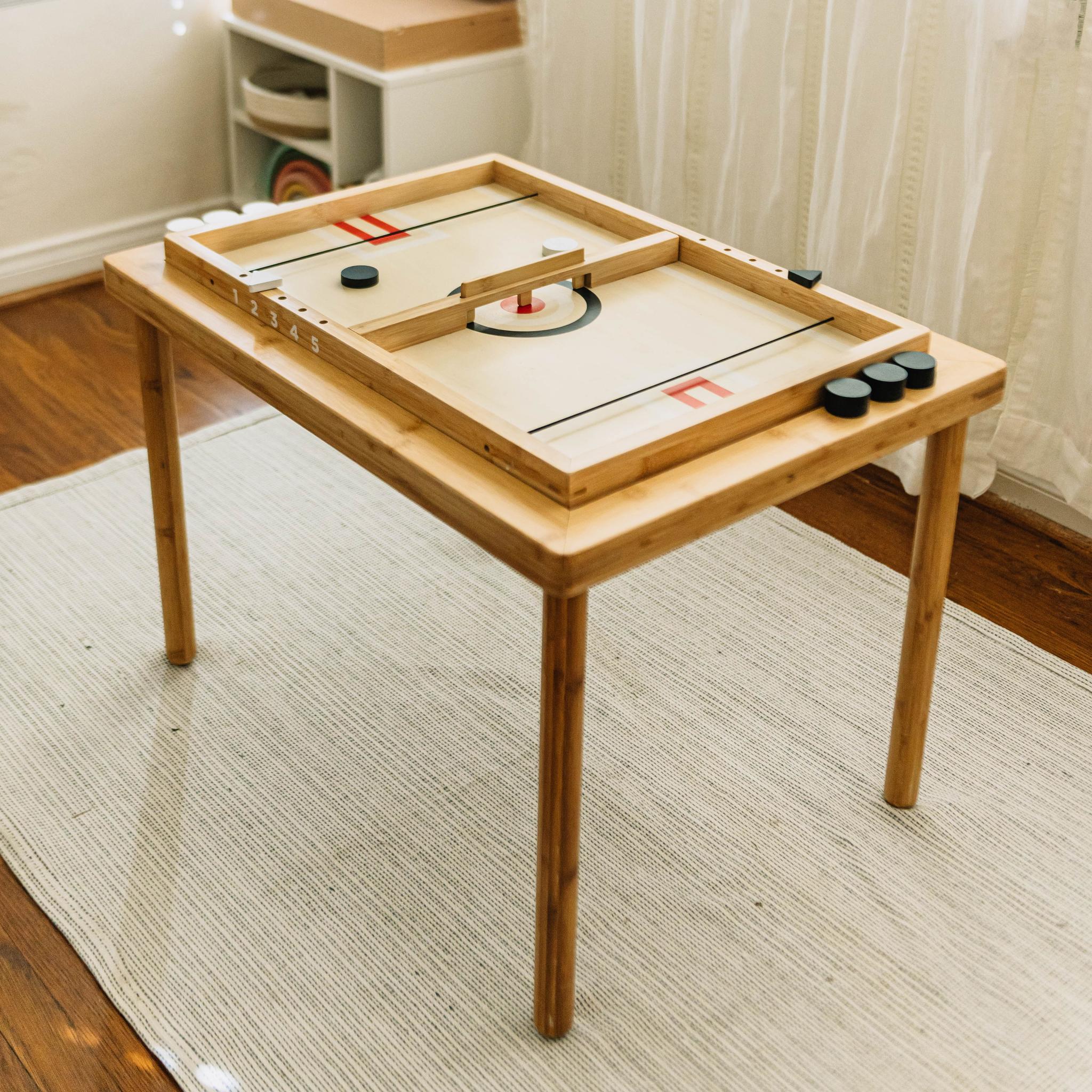 Sling-a-Ling Hockey Game set into a wooden activity table on a woven rug, pucks stacked at one corner